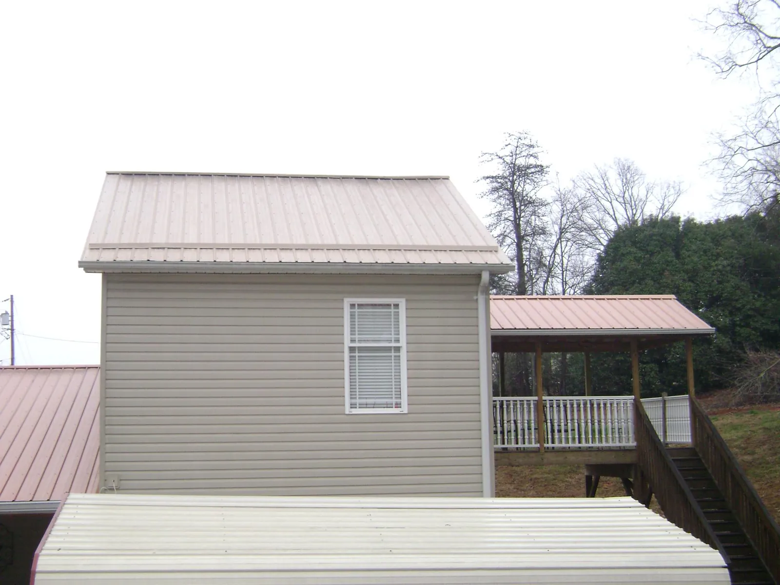 Tan metal roofs on a two story addition and attached porch, from a Roof Replacement job in Ashland